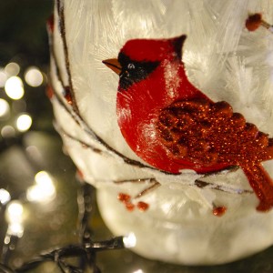 Χριστουγεννιάτικη σύνθεση κόκκινου καρδηνάλιου με γυάλινη μπάλα και κηροπήγιο