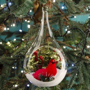 Γυάλινη Χριστουγεννιάτικη μπάλα με κόκκινο διακοσμητικό καρδινάλιο σε χιόνι και πράσινα φύλλα 20 εκ