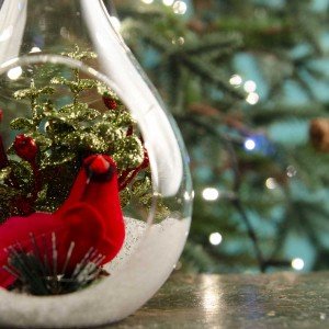 Γυάλινη Χριστουγεννιάτικη μπάλα με κόκκινο διακοσμητικό καρδινάλιο σε χιόνι και πράσινα φύλλα 20 εκ